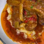 Tender oven baked BBQ ribs garnished with a tasty sauce on a platter.