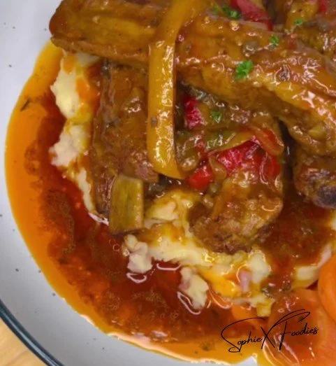 Tender oven baked BBQ ribs garnished with a tasty sauce on a platter.