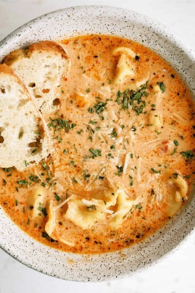 Bowl of Tomato Tortellini Soup with fresh basil and parmesan