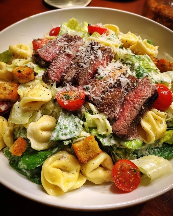 Tortellini and steak Caesar salad served in a bowl with greens