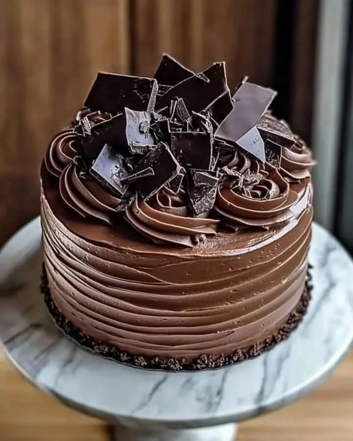 Delicious slice of triple chocolate cake topped with chocolate ganache and cocoa