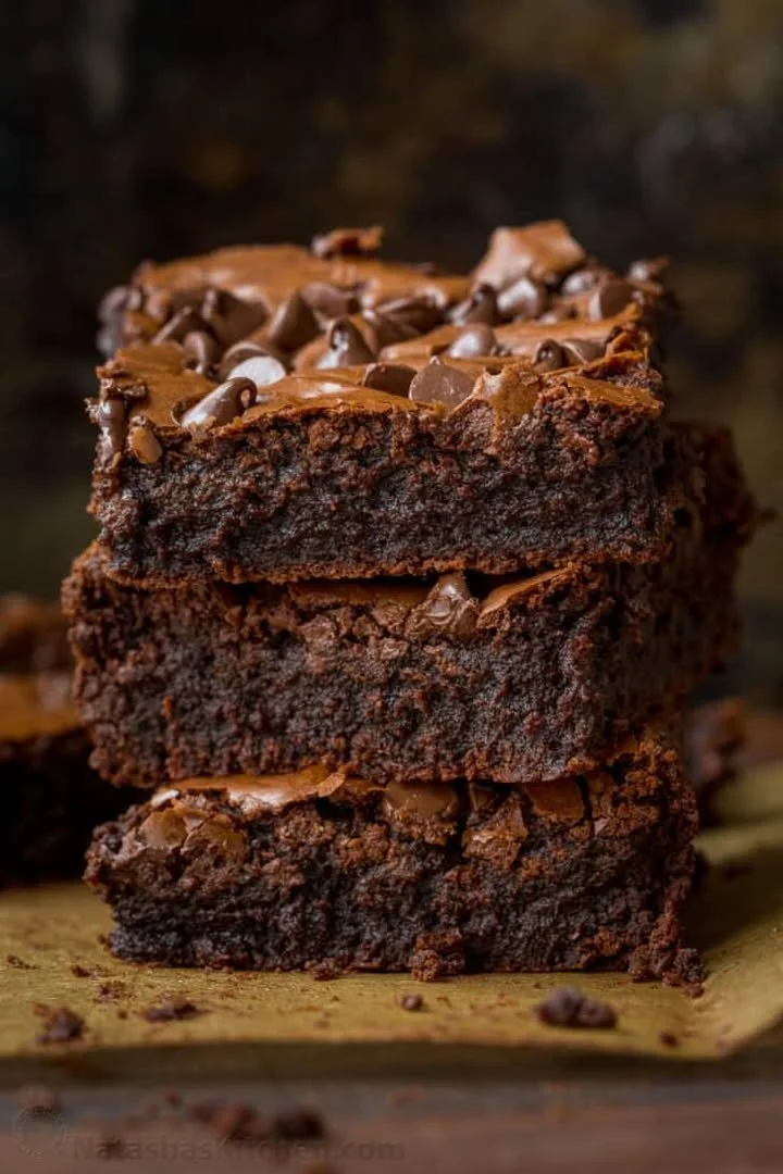 A plate of ultimate fudgy brownies with rich chocolate drizzles on top.