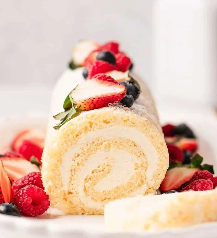 Vanilla cake roll with whipped cream filling, beautifully garnished on a plate