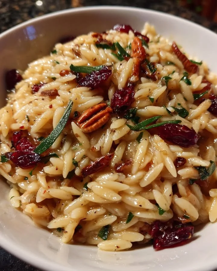Warm Cranberry Pecan Orzo dish garnished with sage and pecans