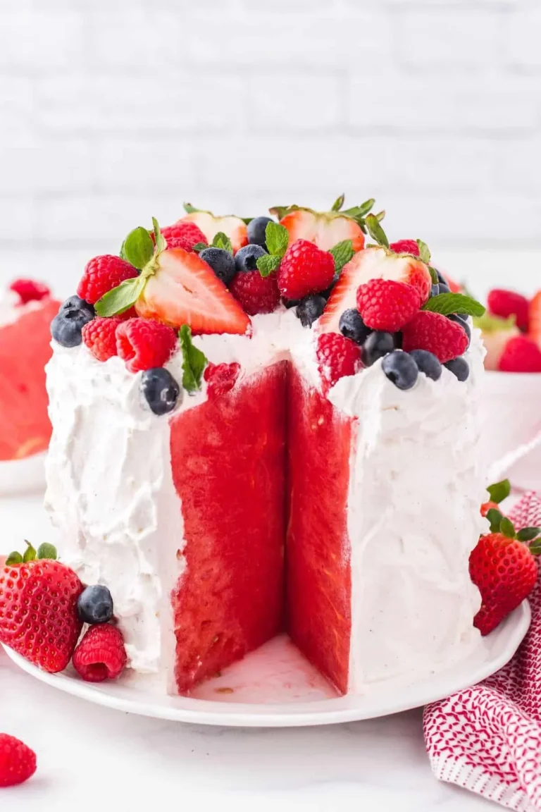 Slice of colorful Watermelon Cake topped with whipped cream and fresh fruits