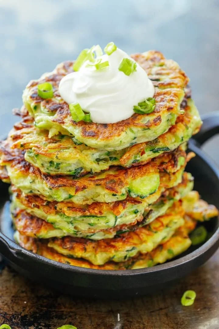 Crispy zucchini fritters served on a plate with dipping sauce