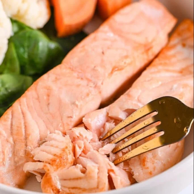 Crispy air fryer salmon fillet with herbs and spices on a plate.