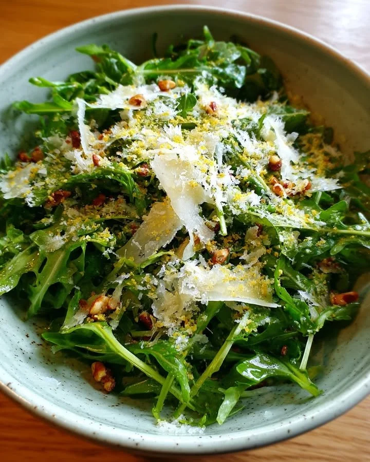 Delicious arugula salad topped with lemon dressing and Parmesan cheese