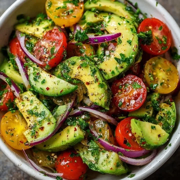 Fresh avocado tomato salad with herbs on a wooden table