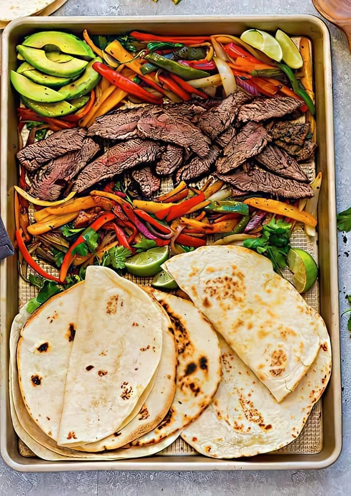 Plate of beef fajitas with colorful veggies and soft tortillas.