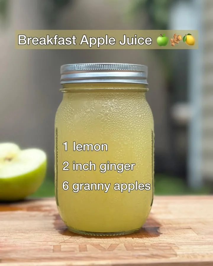Glass of fresh breakfast apple juice on a table with apples in the background
