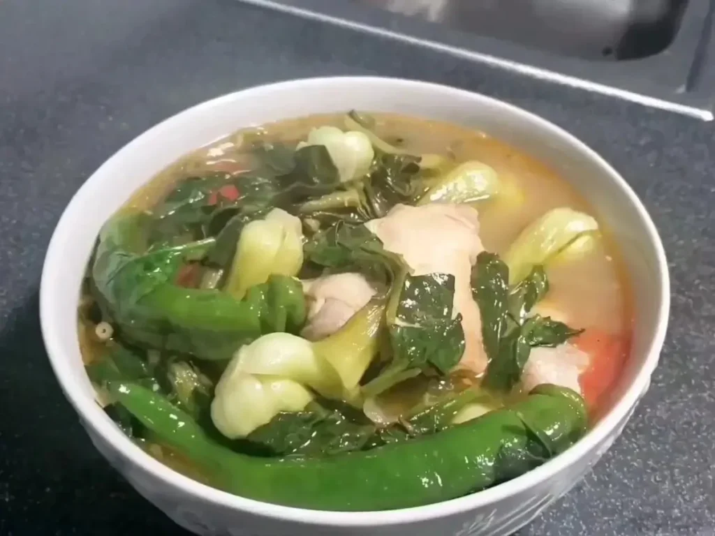 Bowl of Chicken Sinigang with fresh vegetables and herbs