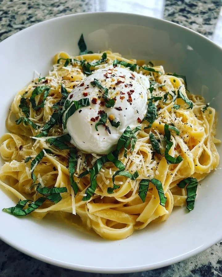 Creamy basil and garlic pasta dish garnished with burrata cheese