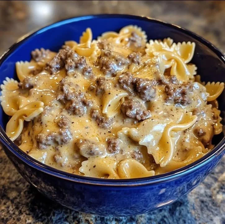 Creamy beef and bowtie pasta dish garnished with herbs
