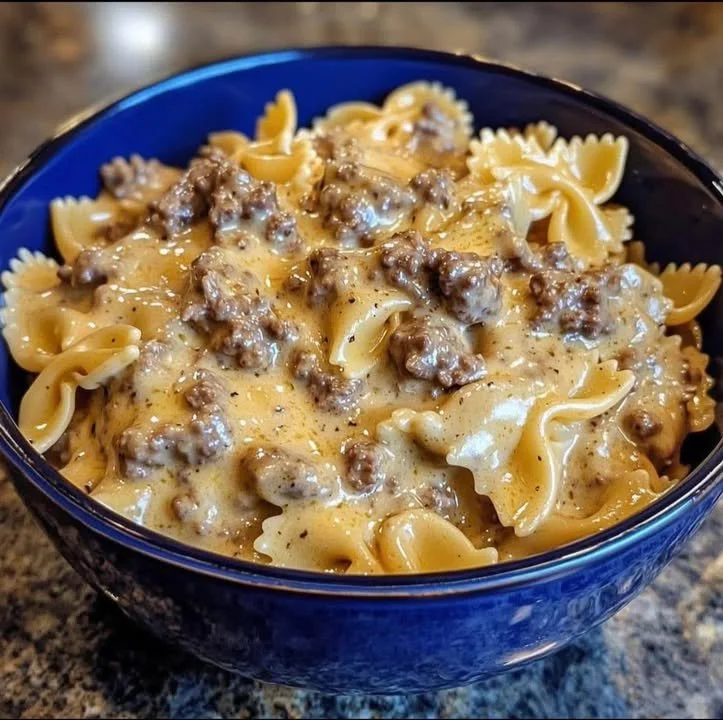 Creamy beef and bowtie pasta served in a bowl with fresh herbs and parmesan