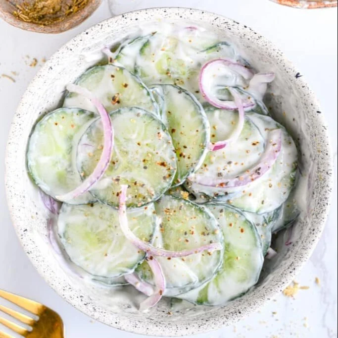 Creamy cucumber yogurt salad garnished with fresh herbs in a bowl