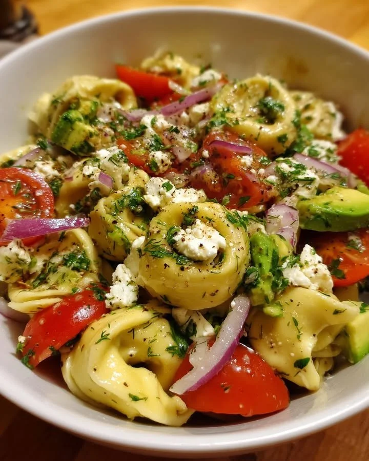 Creamy feta and avocado tortellini salad with herb dressing in a bowl