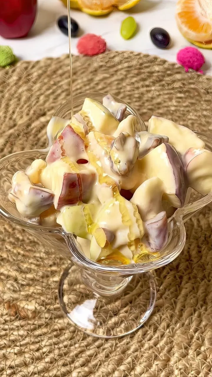 Creamy fruit salad topped with honey drizzle in a bowl