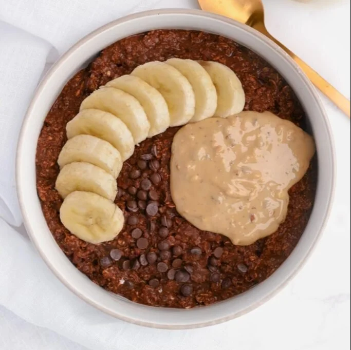 Bowl of creamy high-calorie oatmeal topped with fruits and nuts