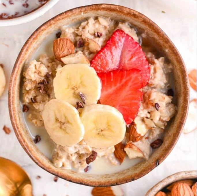 A bowl of creamy protein oatmeal topped with fruits and nuts.