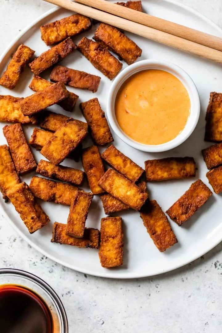 Crispy air fryer tofu served on a plate, garnished with herbs.