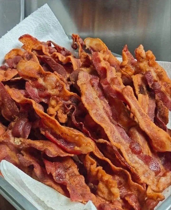 Plate of perfectly crispy bacon strips garnished with herbs
