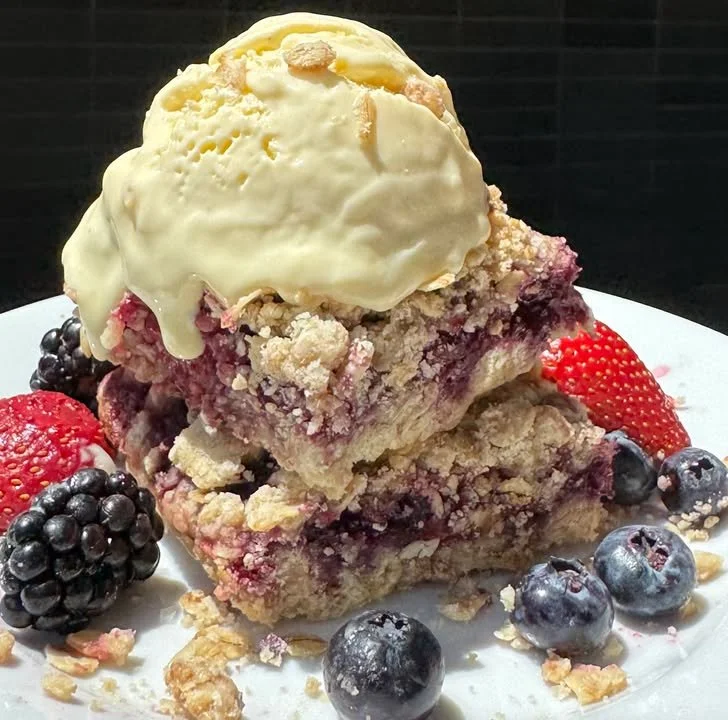 A plate of delicious crumble bars, topped with fruit and a crunchy crumb topping