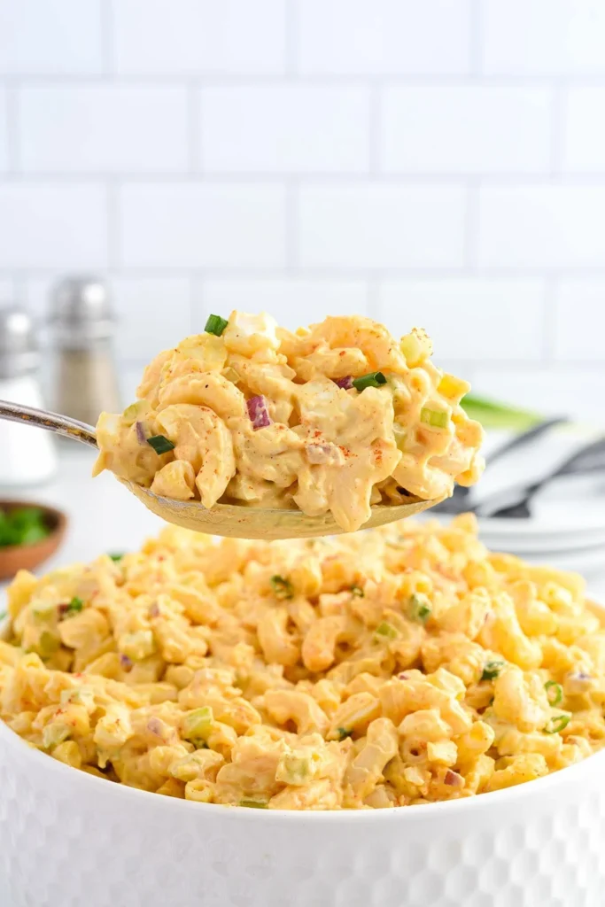 Bowl of Deviled Egg Pasta Salad with vibrant ingredients and garnishes.
