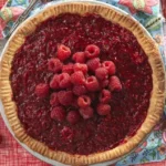 Freshly baked raspberry pie with vibrant red raspberries on top
