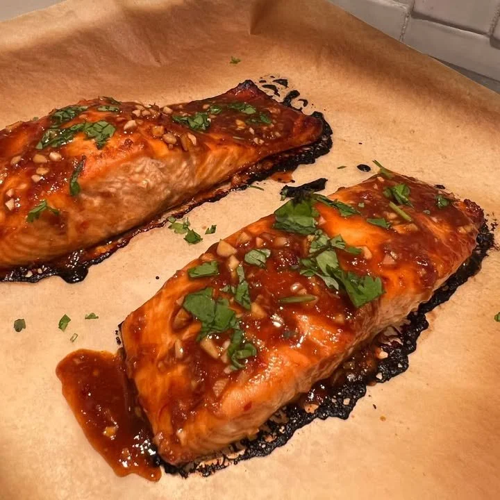 Cooked Gochujang Salmon garnished with herbs on a plate