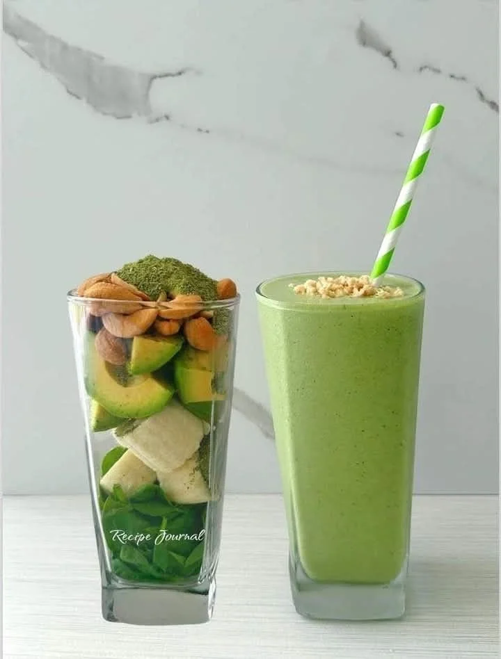 Healthy green avocado spinach smoothie in a glass with ingredients