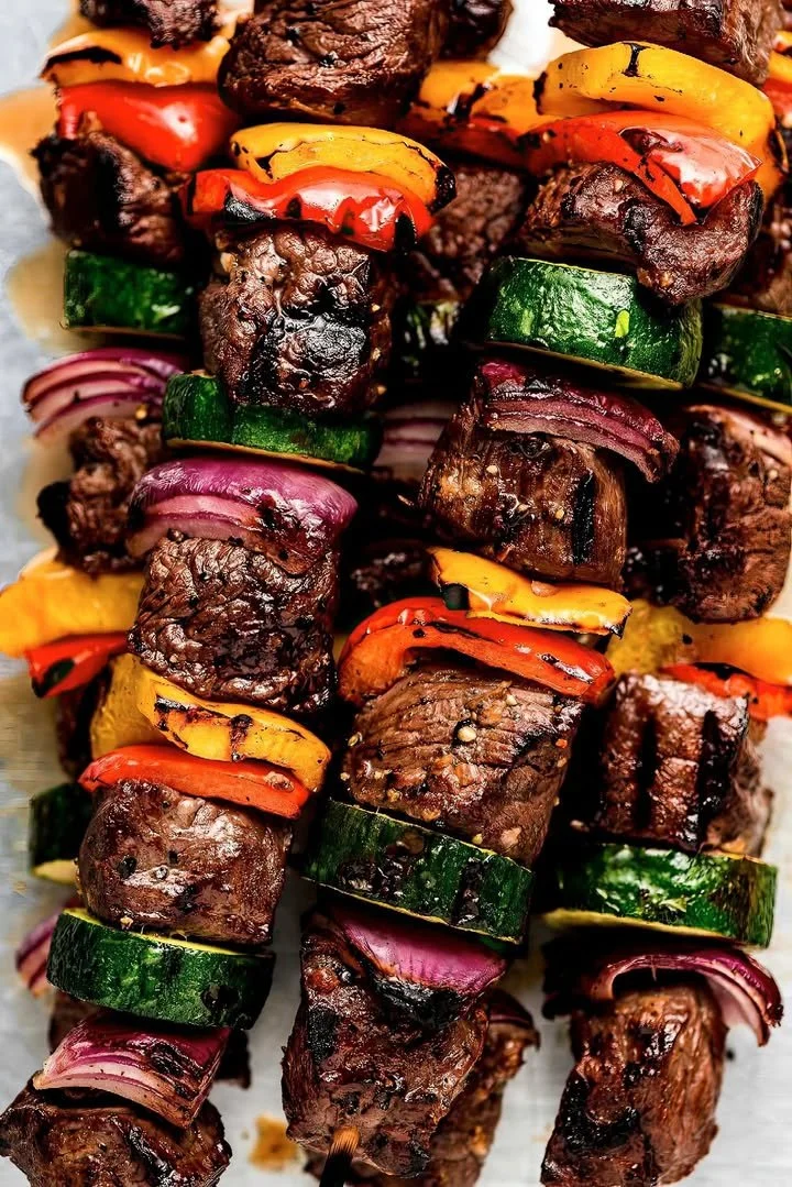 Grilled beef kabobs skewered with colorful peppers and onions on a barbecue grill.