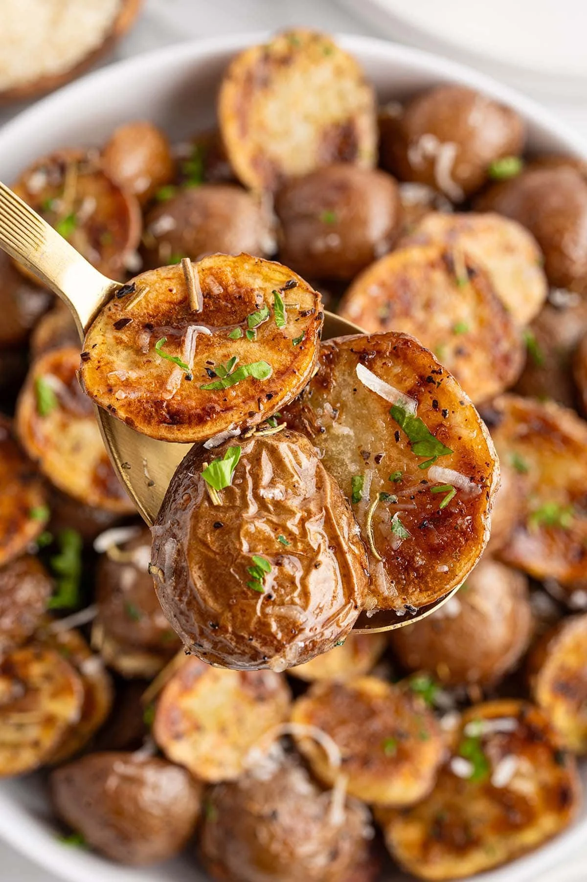 Grilled herb-infused potatoes garnished with fresh herbs on a barbecue grill.