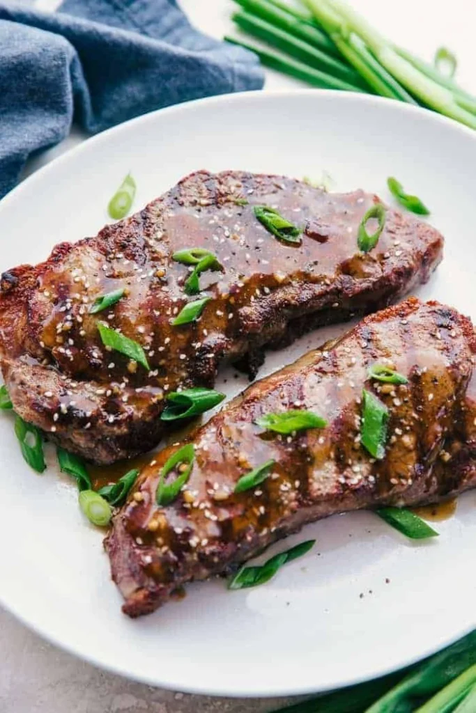 Grilled rib eye steak drizzled with ginger teriyaki sauce on a plate