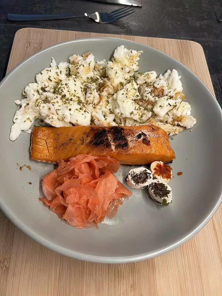 Grilled salmon served with cauliflower, pickled ginger, and goat cheese balls