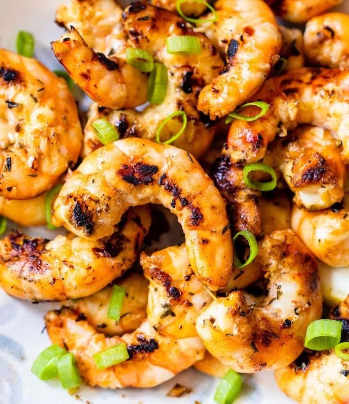 Delicious grilled shrimp served on a platter with fresh herbs and lemon slices