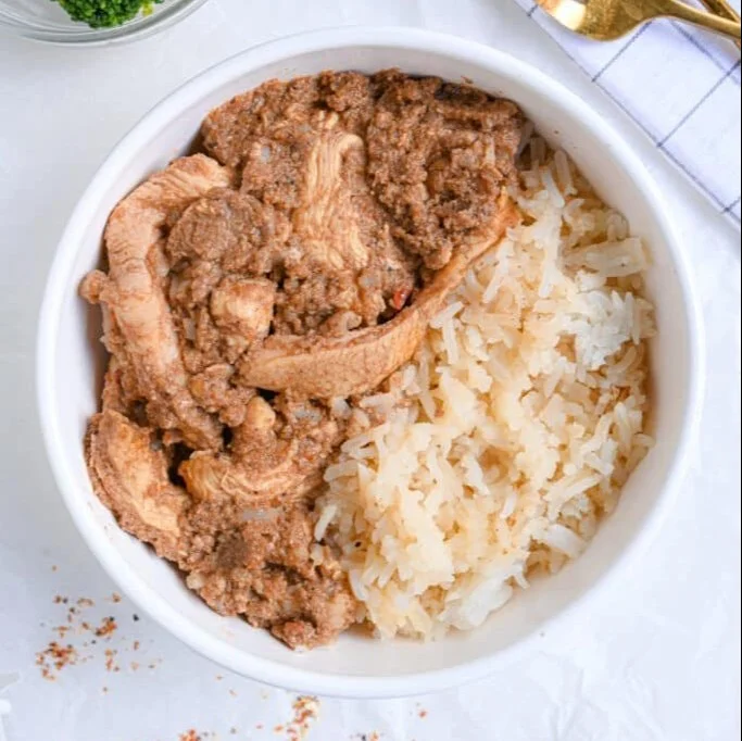 High protein chicken curry dish served in a bowl with rice and herbs