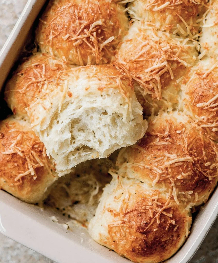Freshly baked homemade cheddar cheese rolls on a wooden table.