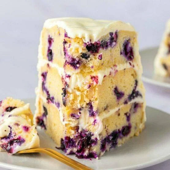 Sliced Lemon Blueberry Cake topped with fresh blueberries and lemon zest.
