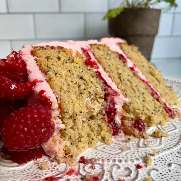 A slice of Lemon Raspberry Cake topped with fresh raspberries and lemon zest.