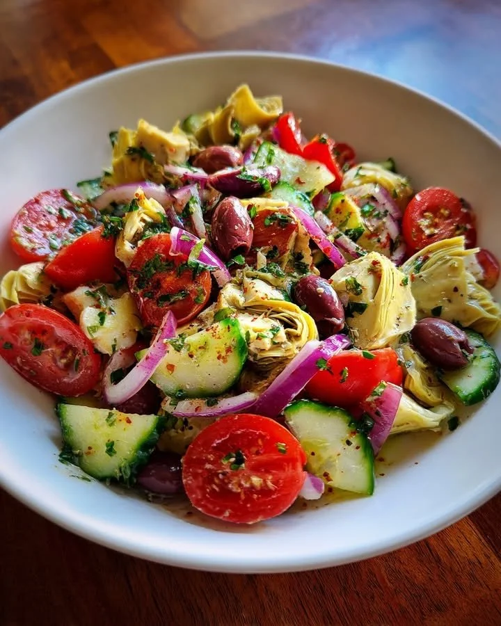 Fresh marinated artichoke salad with herbs and vegetables in a bowl