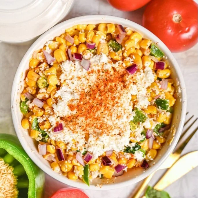 Dish of vibrant Mexican street corn salad with corn, lime, and spices.