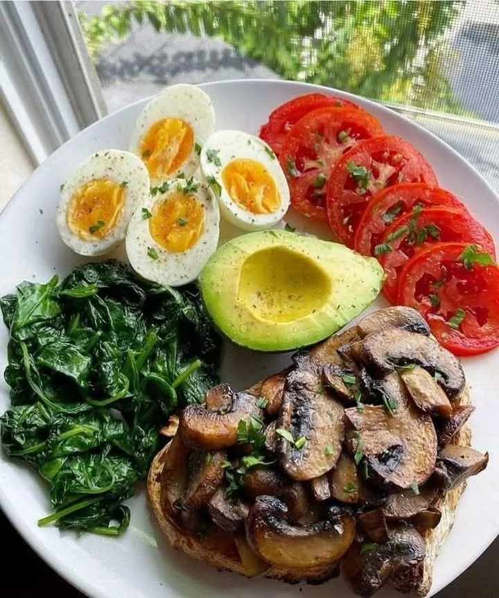Delicious mushroom toast topped with eggs, spinach, and avocado for a healthy meal.