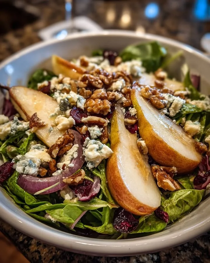 Pear, blue cheese, and walnut salad served in a bowl with fresh greens