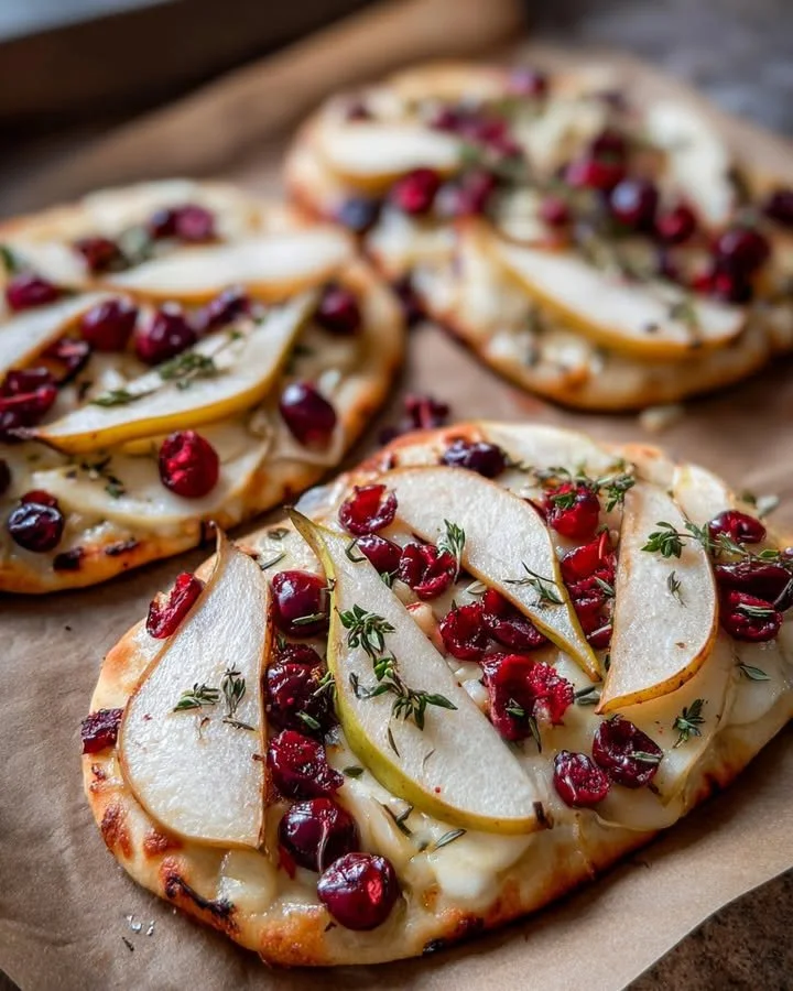 Delicious Pear, Brie, and Cranberry Flatbread topped with fresh thyme.