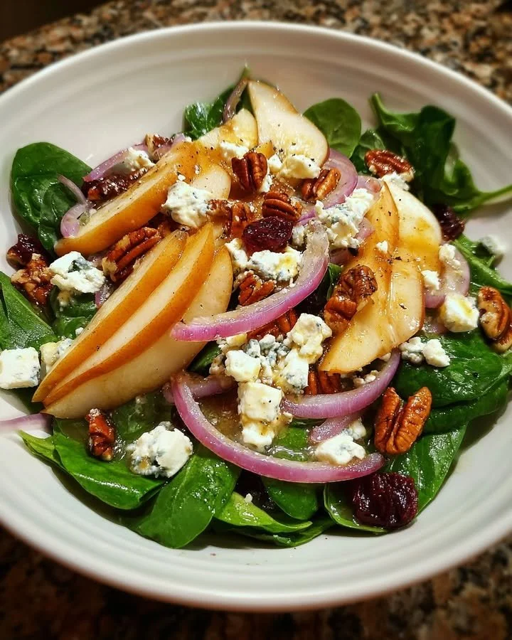 Pear and goat cheese spinach salad with walnuts and vinaigrette dressing.