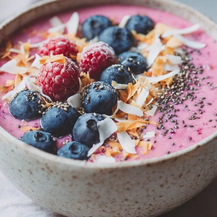 Pink berry smoothie bowl topped with fresh berries and granola.