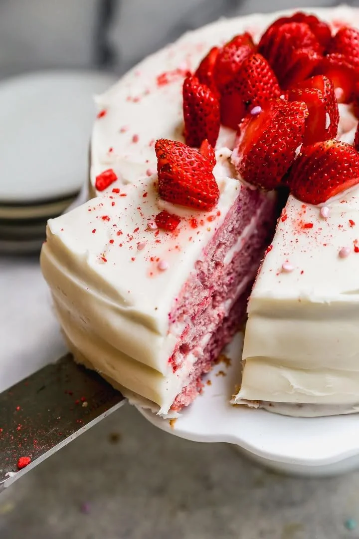 A beautifully decorated pink cake topped with cream cheese frosting.