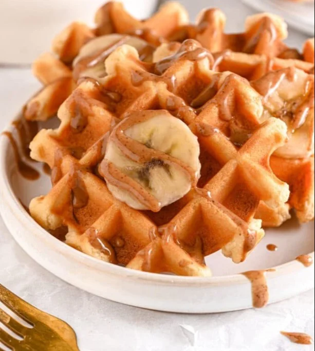 Stack of delicious protein-packed waffles topped with berries and syrup