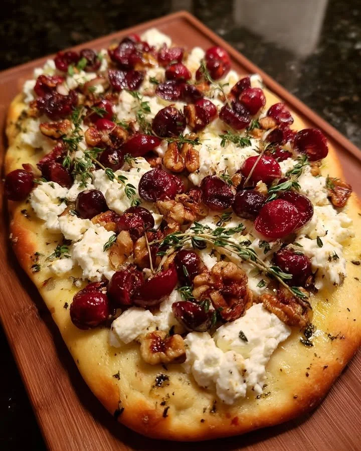 Delicious roasted cranberry and goat cheese flatbread garnished with fresh herbs
